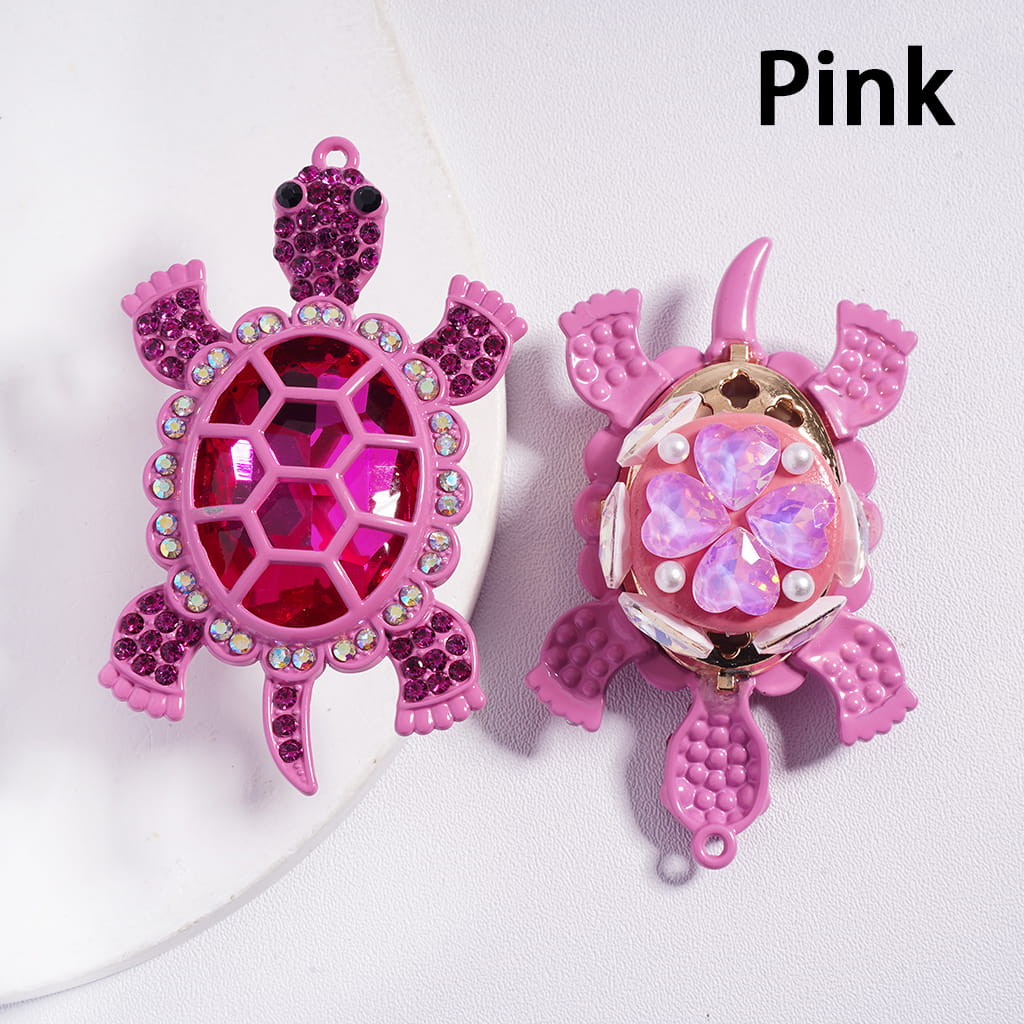 Two pink turtle-shaped charms with decorative elements on a white background.