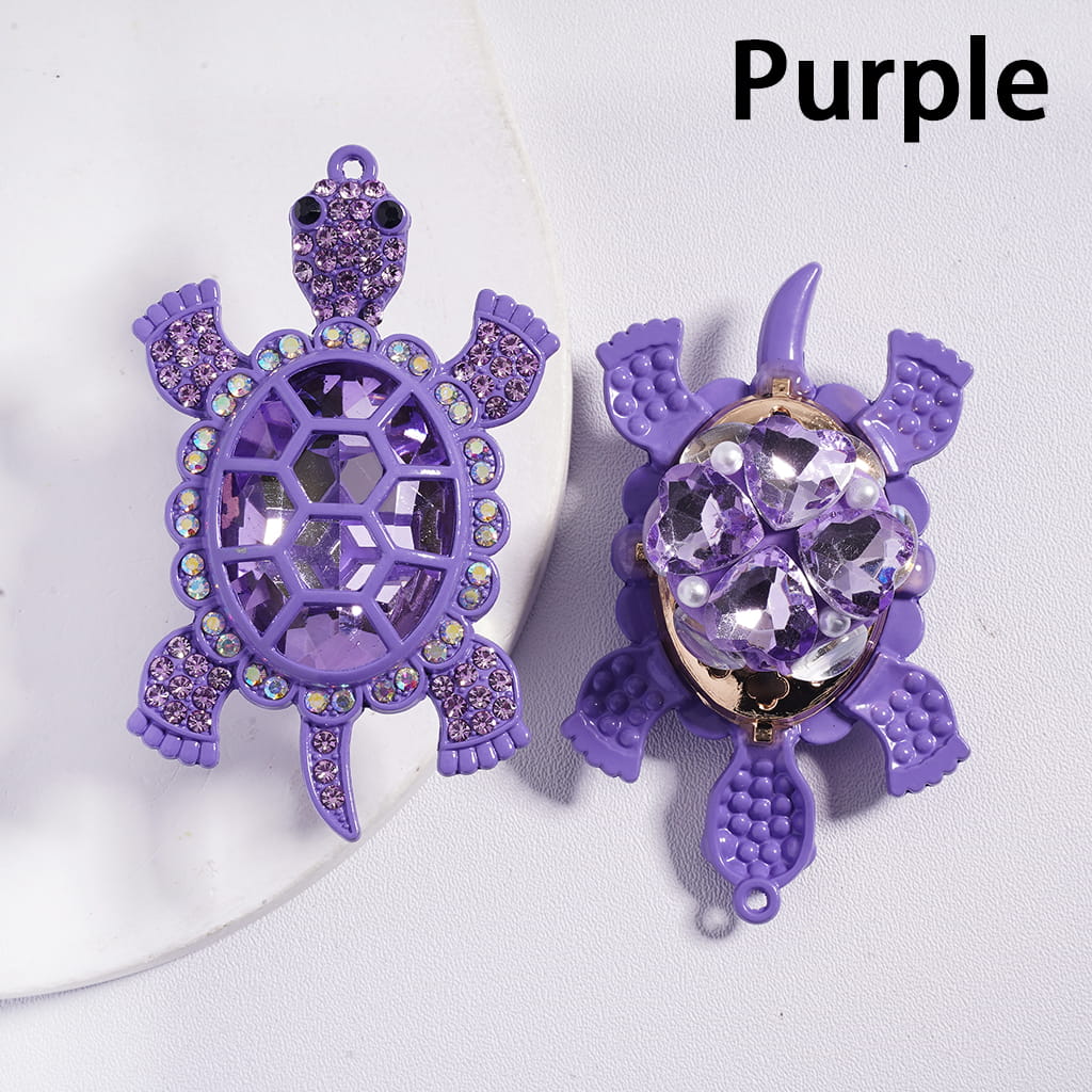 Purple turtle-shaped jewelry with rhinestones on a white background