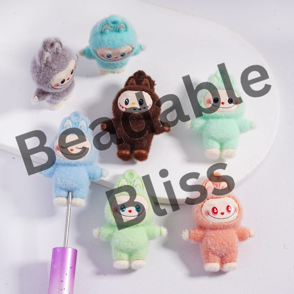 Colorful plush toys on a white background with text indicating size and website.

