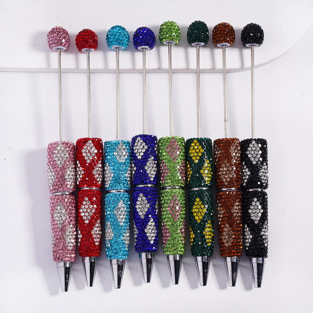 Five decorative pens with colorful gemstones on a white background