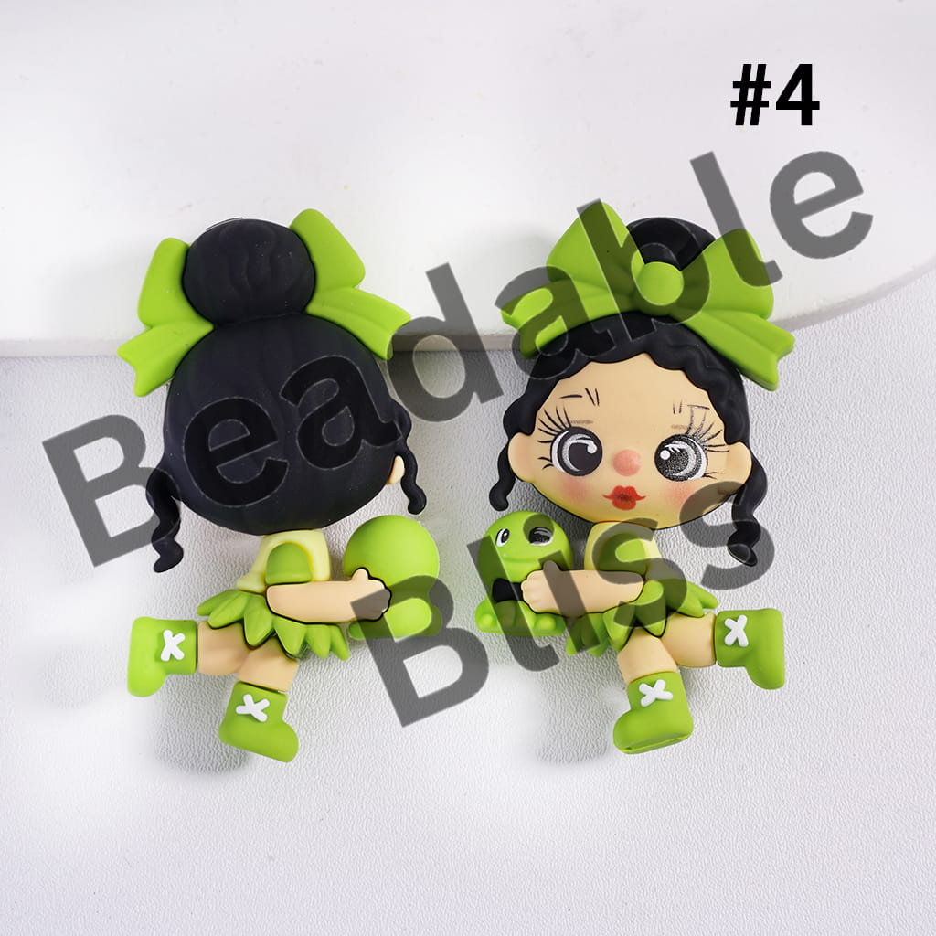 Two green and black character figurines with a bow on a white background.