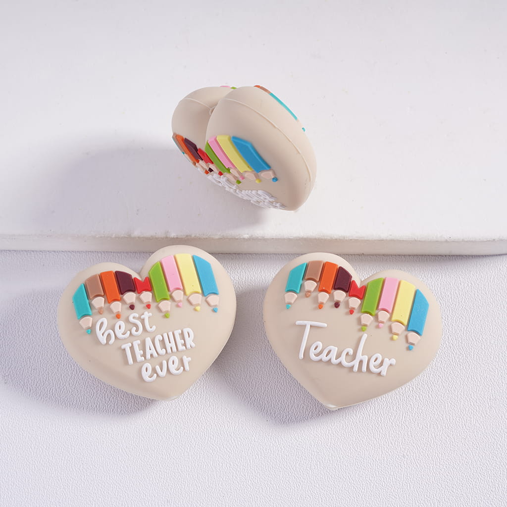Heart-shaped cookie cutters with colorful pencil design and 'best teacher ever' text on a white background