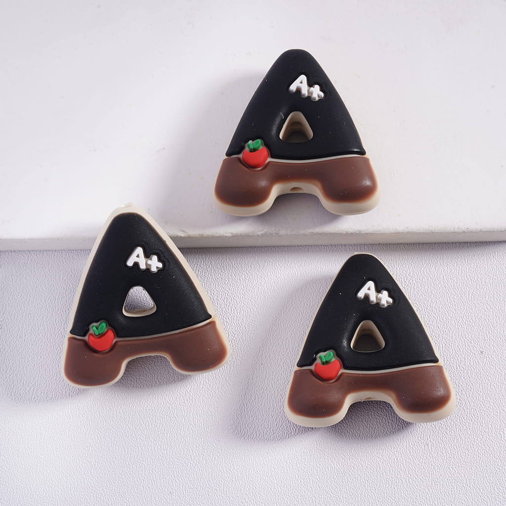 Three letter 'A' shaped cookies with chocolate frosting and red apples on a white background