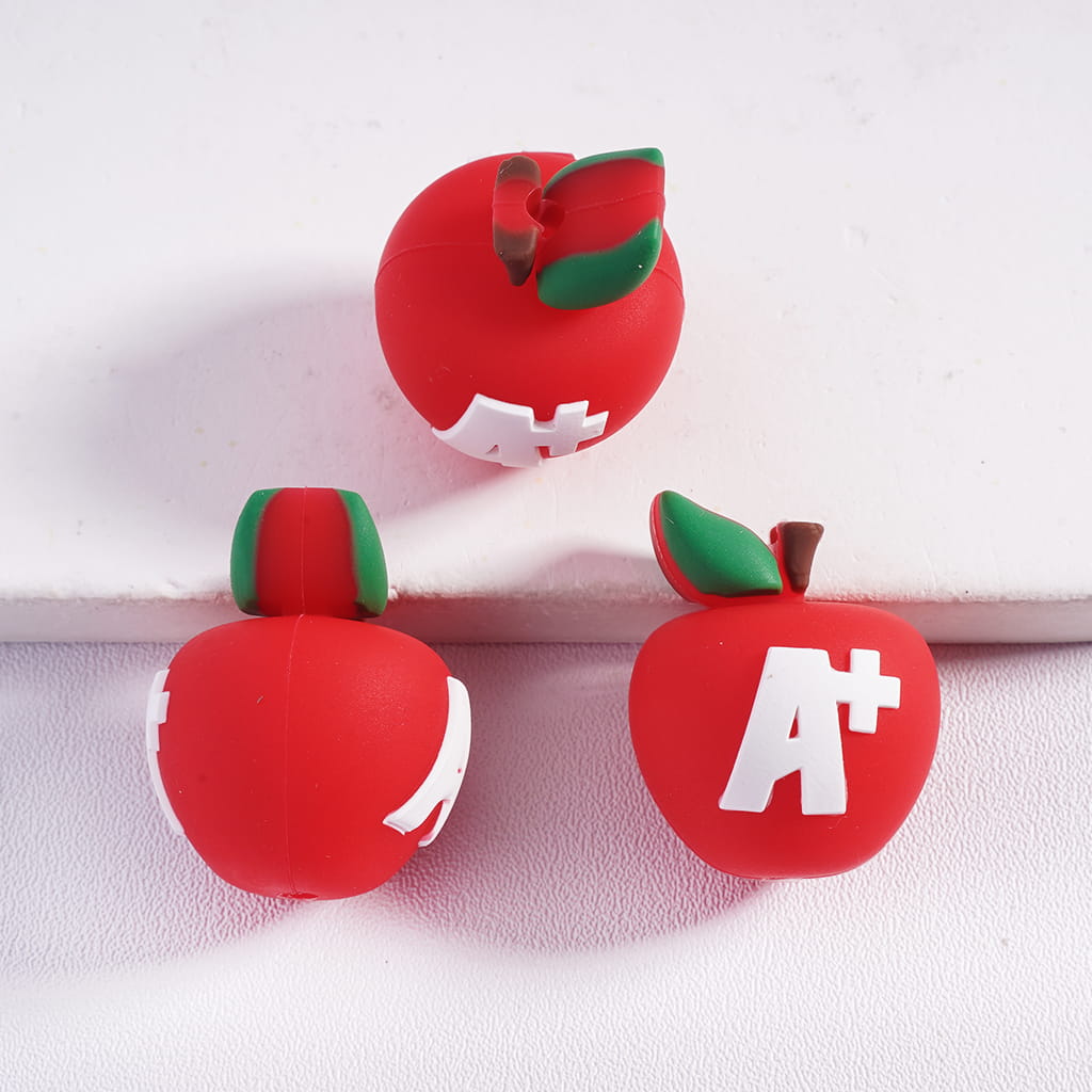 Three red apples with green leaves and white 'A+' symbols on a white background