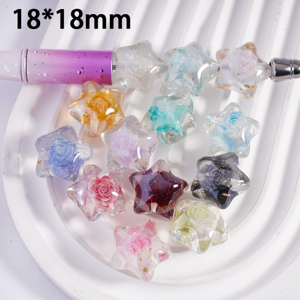 Colorful star-shaped beads on a white plate with a pen for scale.