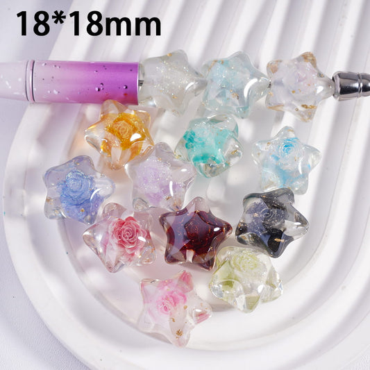 Colorful star-shaped beads on a white plate with a pen for scale.