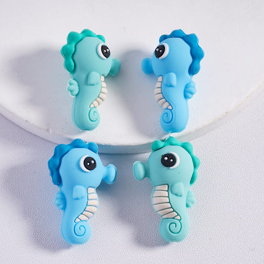 Four blue and green seahorse-shaped objects on a white background