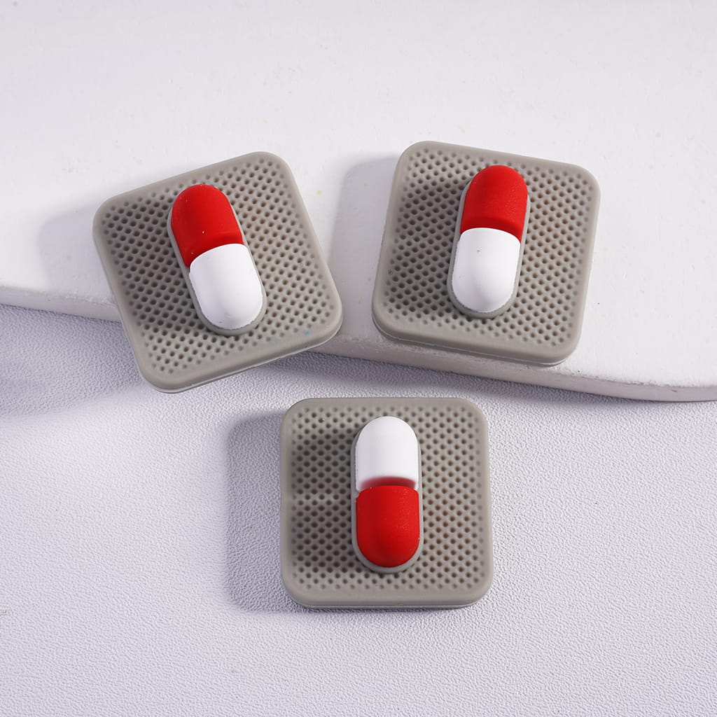 Three square coasters with red and white pill-shaped designs on a light gray background