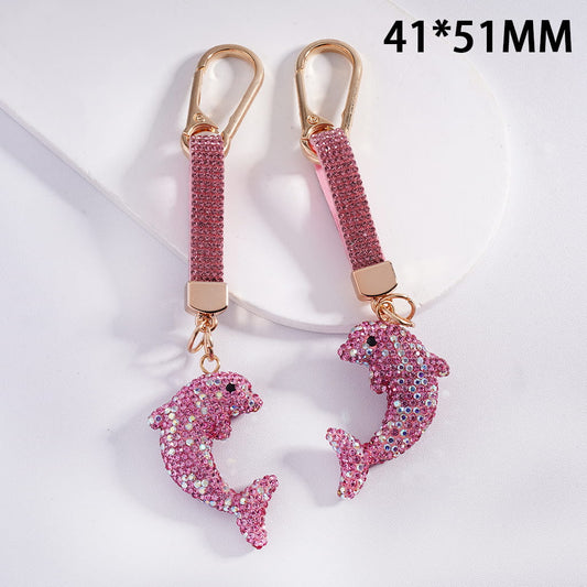Pink dolphin keychains with glittery details on a white background