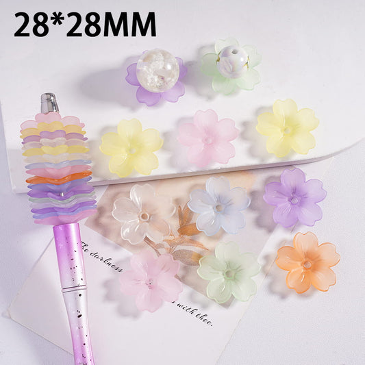 Colorful flower-shaped hair clips on a white surface with a pen and text.