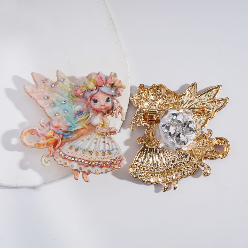 Decorative brooches with fairy design and gold leaf detail on a white background