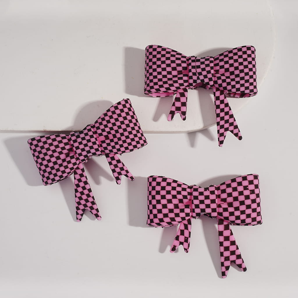 Three pink and black checkered bows on a white background