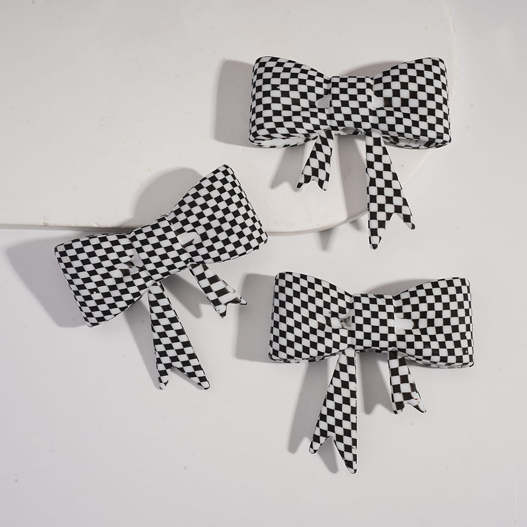 Three black and white checkered bows on a light gray background