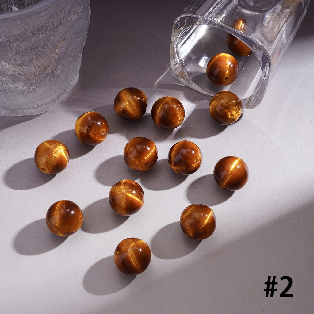 Brown cat's eye beads spilling out of a clear glass container on a white surface.