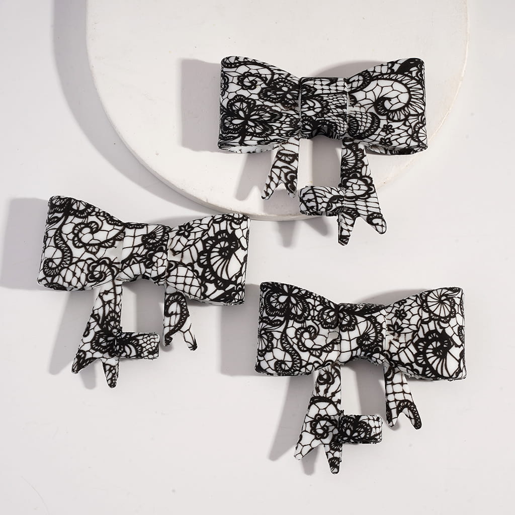Black lace bow-shaped hair clips on a white background