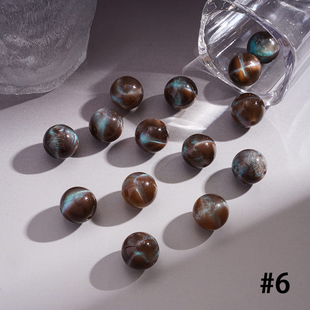 Brown and green marbled beads on a light surface with a clear container.