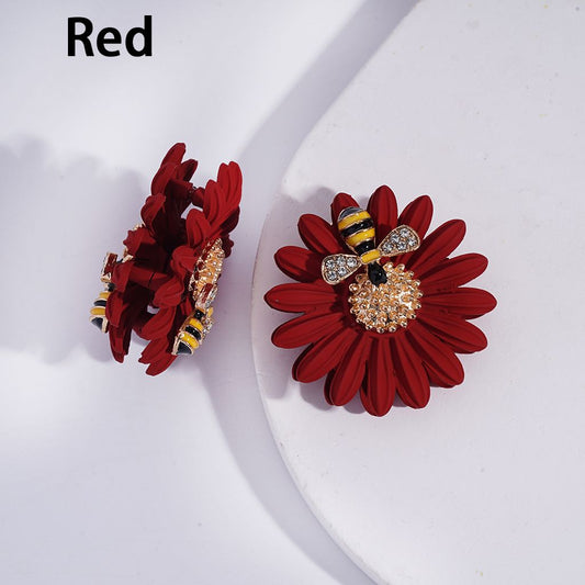 Red flower-shaped earrings with bee design on a white background
