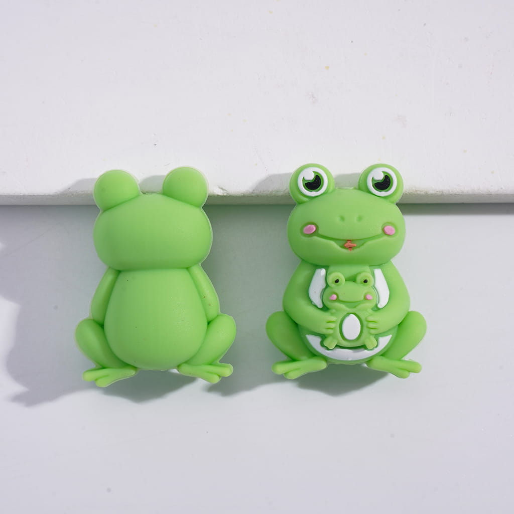 Two green frog-shaped objects on a white background