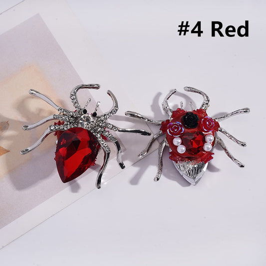 A collection of decorative spider-shaped brooches with various colorful rhinestones and small white pearls, displayed against a white background.

