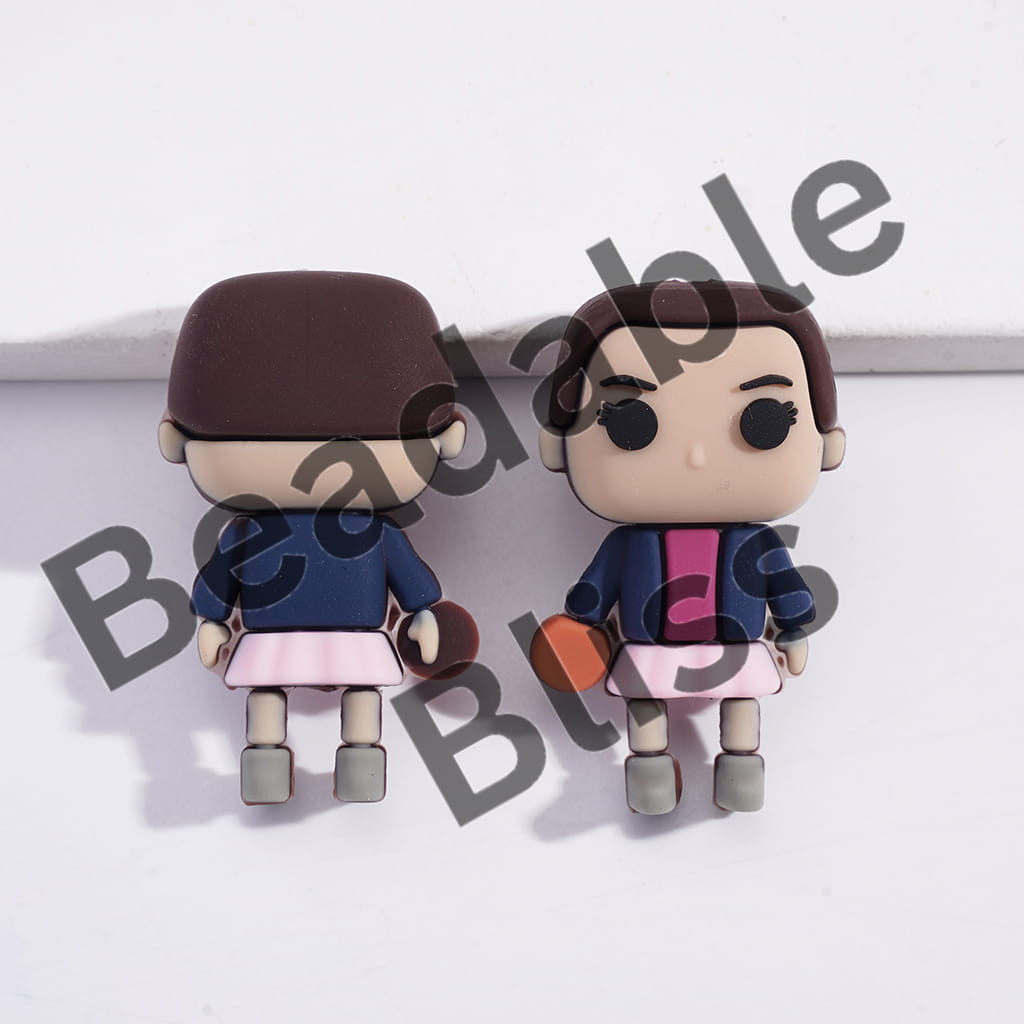 Two small figurines of a person with a hat and another with a pink top and brown skirt on a white background.