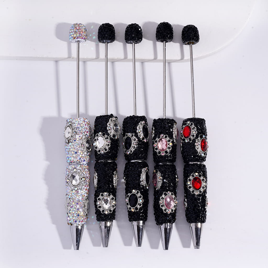 Set of decorative pens with black embellishments and gemstones on a white background