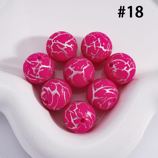 Pink marbled beads on a white surface with a heart-shaped object.