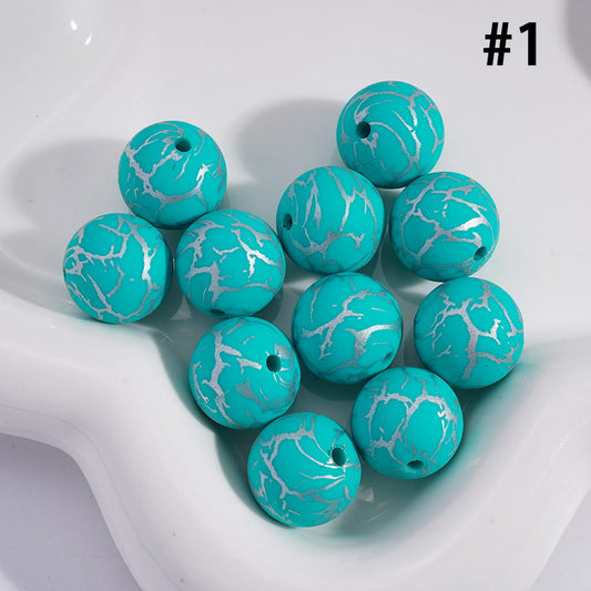Turquoise beads with silver marbled pattern on a white surface