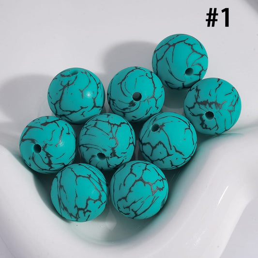 Turquoise beads with black marbled pattern on a white surface