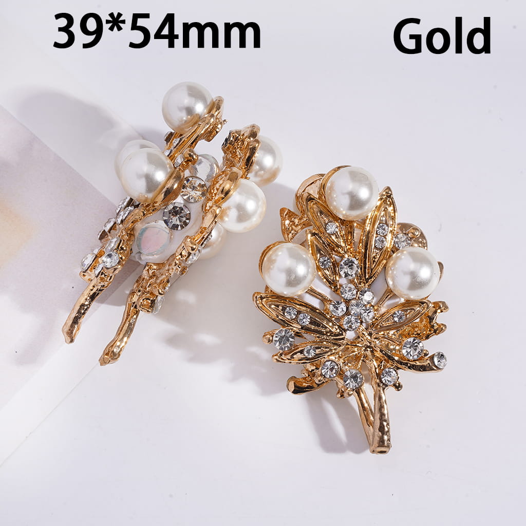 Gold leaf-shaped earrings with pearls and crystals on a white background