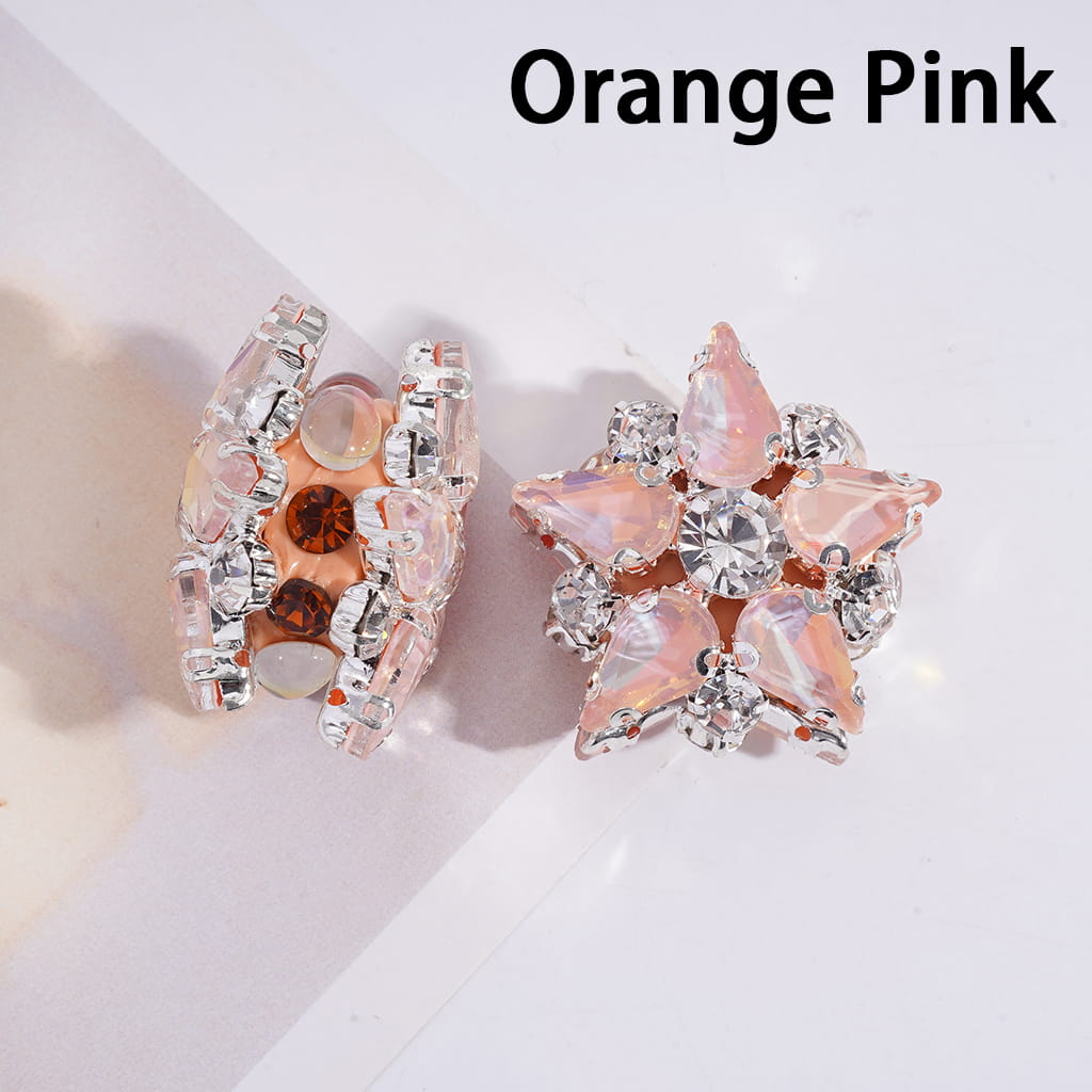 Pair of orange pink earrings with clear stones on a light background