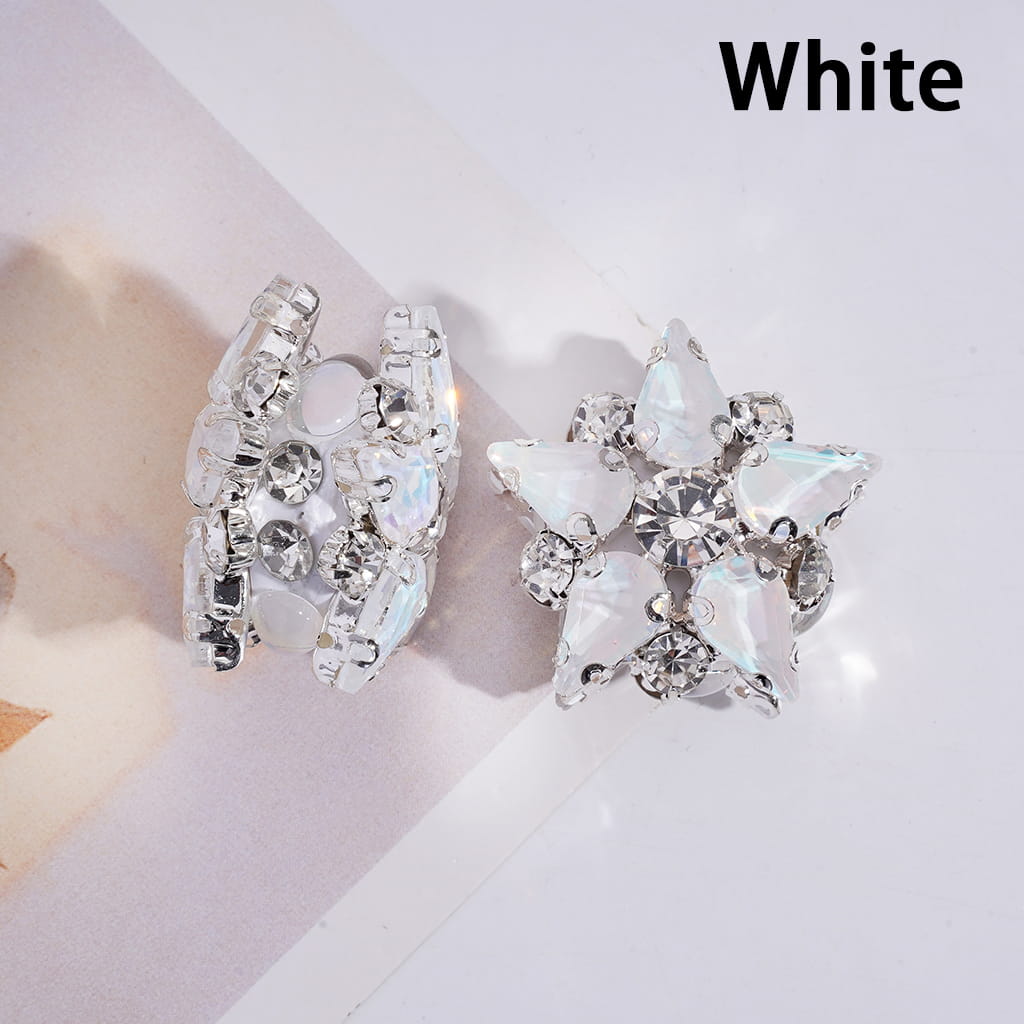 White butterfly-shaped earrings with clear gemstones on a light pink background.