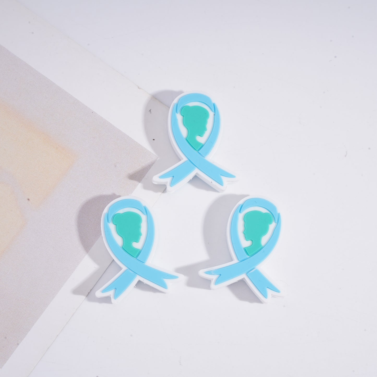 Three blue and green ribbon-shaped objects on a light background