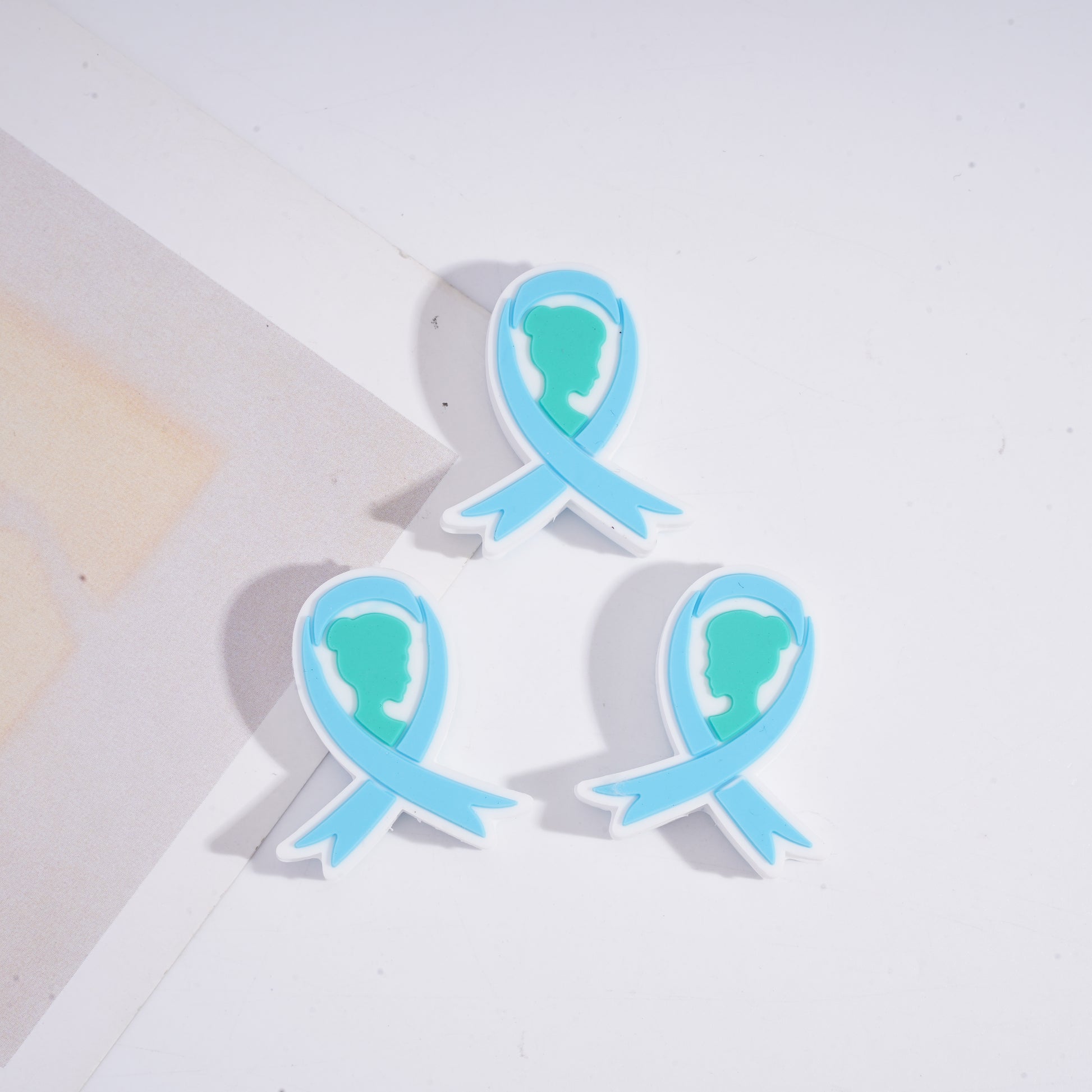 Three blue and green ribbon-shaped objects on a light background