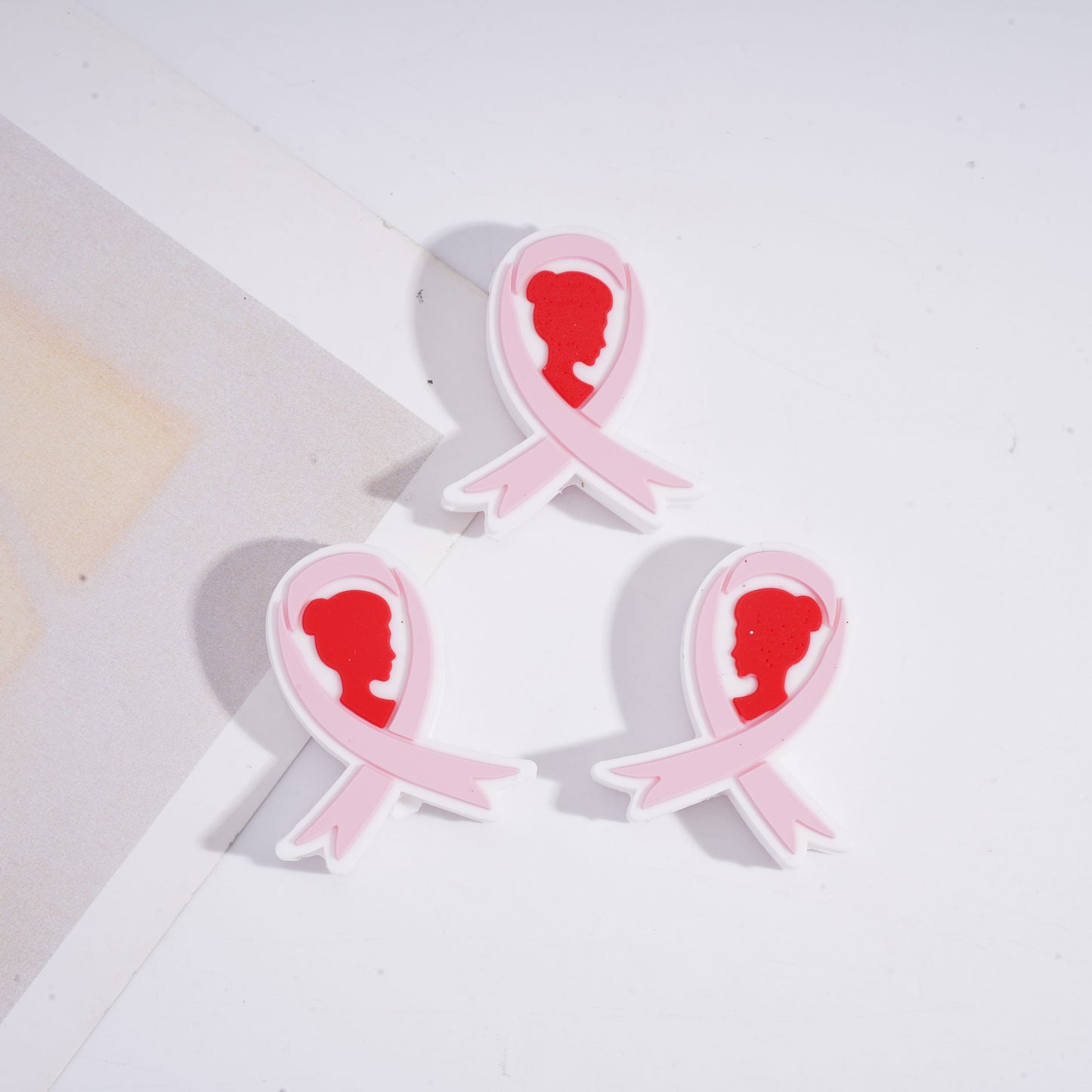 Pink ribbons with silhouette profiles on a white background