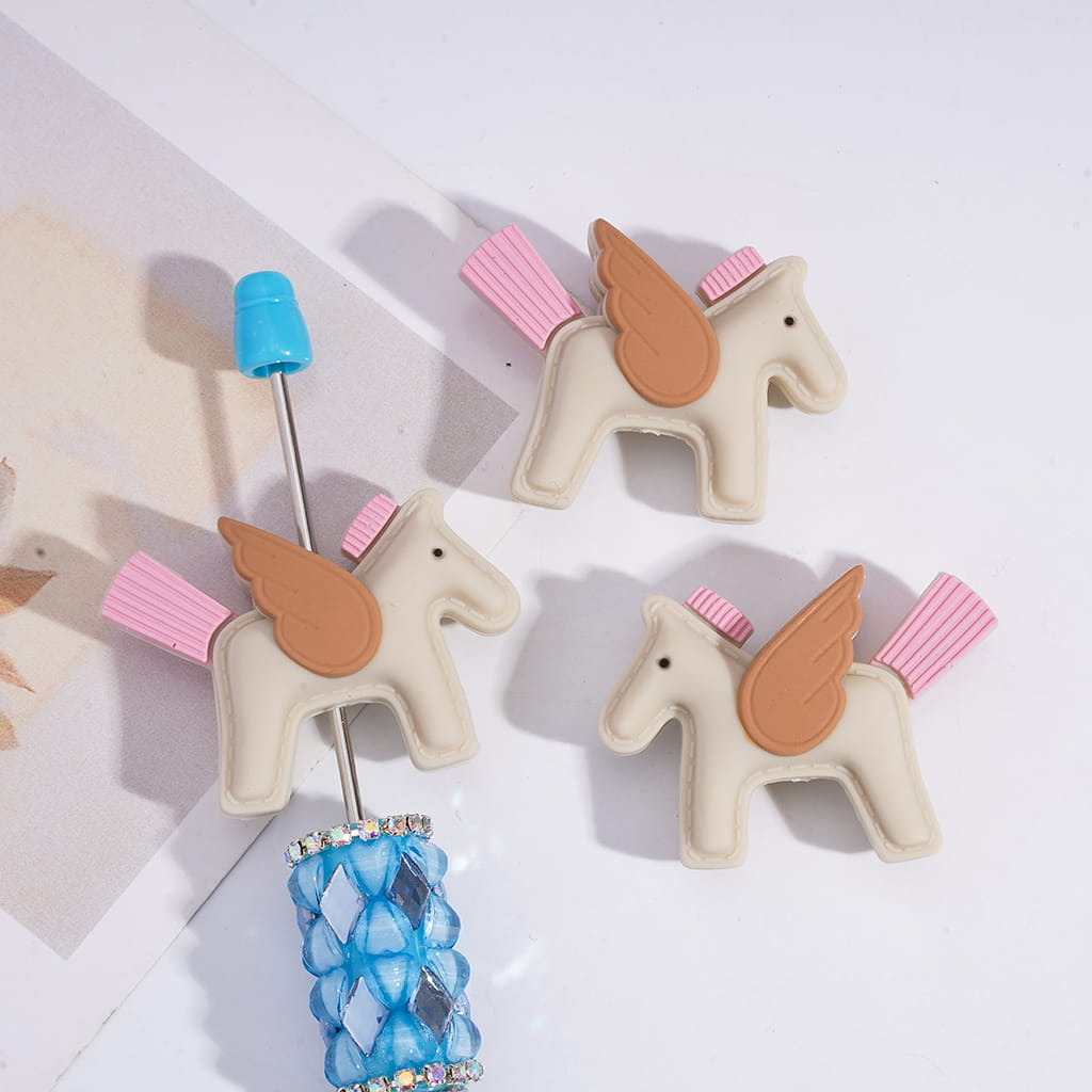 Unicorn-shaped bottle stoppers with blue and pink accents on a white surface.