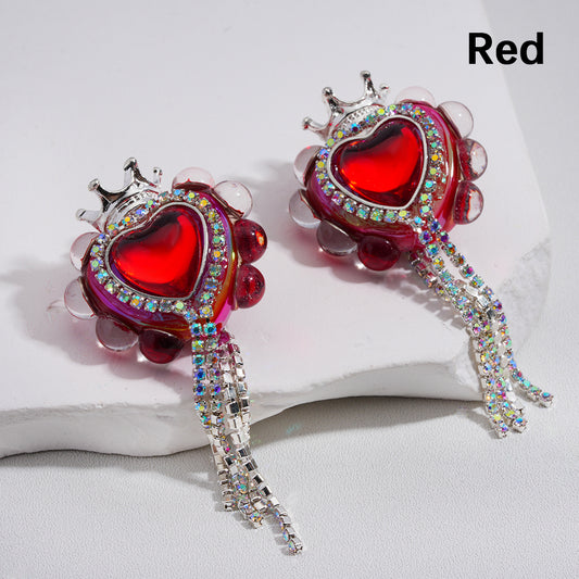 Red heart-shaped earrings with rhinestone details on a light gray background

