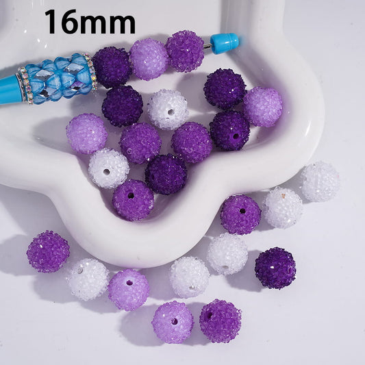 Purple and white beads with a blue tool on a white surface