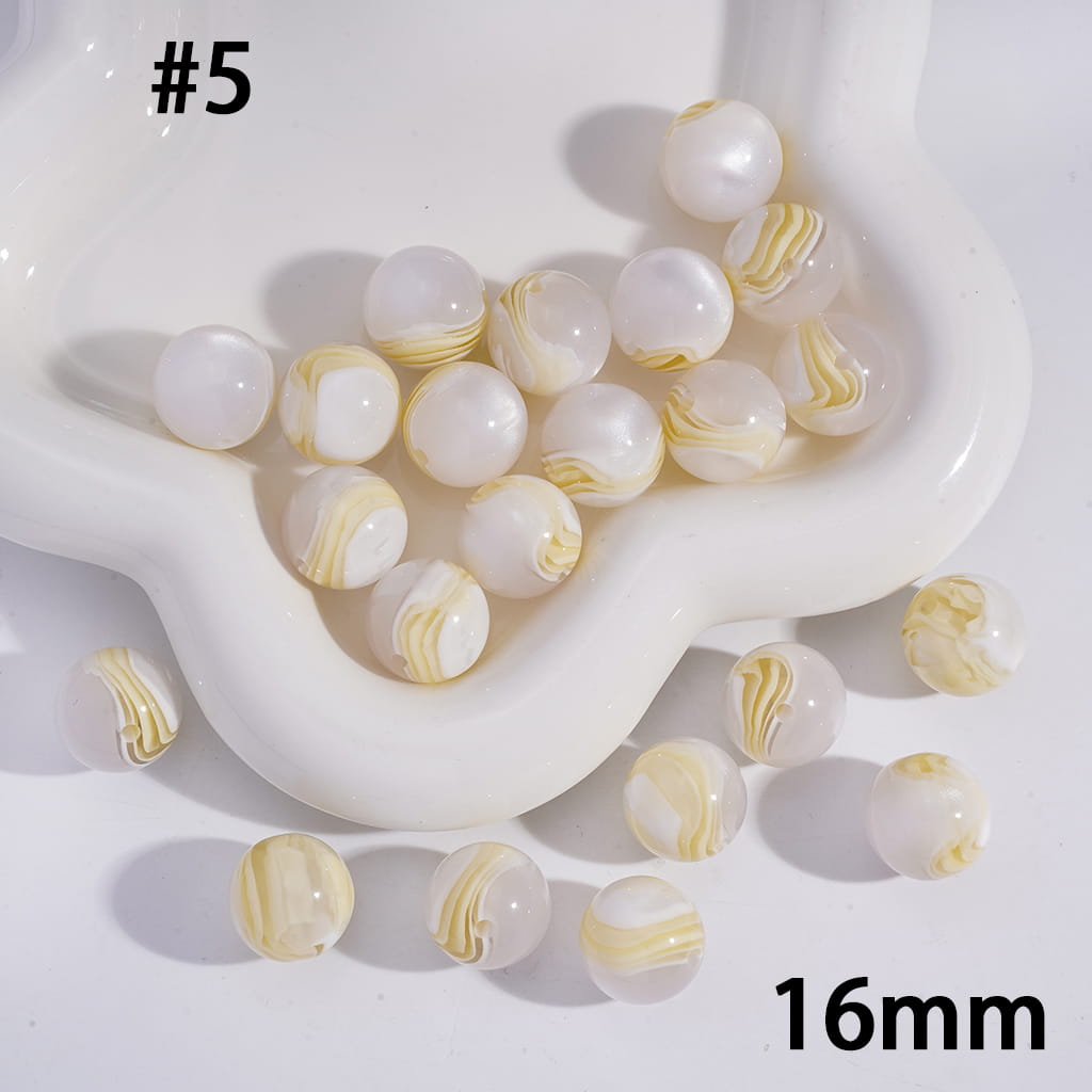 White and gold marbled beads with a white dish on a light background