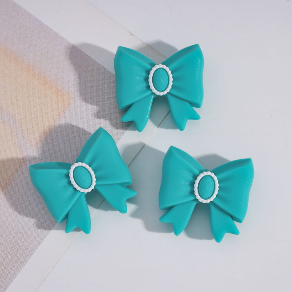 Three turquoise bows with white centers on a light gray background