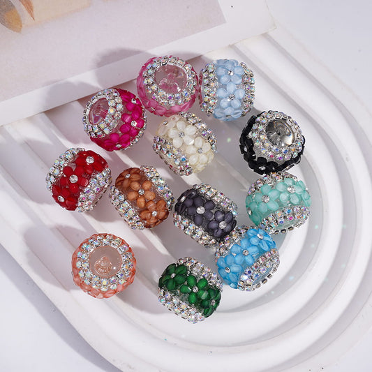 A collection of multicolored round acrylic beads designed for keychains, displayed alongside a pink pen for scale.

