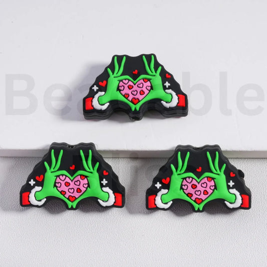 Three decorative items with green antlers and pink hearts on a white background

