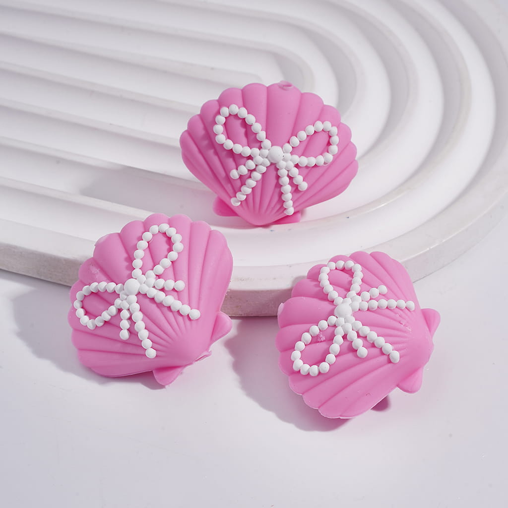 Three pink shell-shaped hair accessories with white pearl bows on a light background

