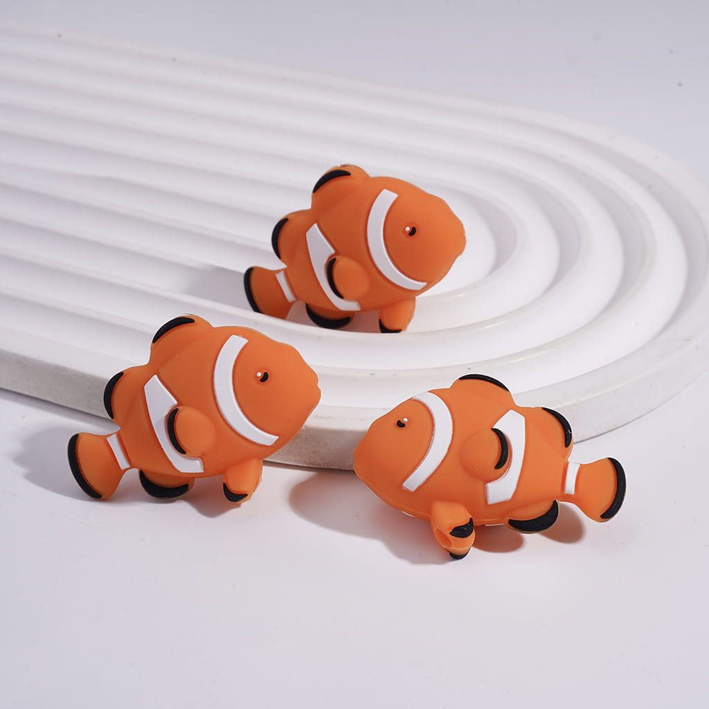 Three orange and black clownfish-shaped cable clips on a white background

