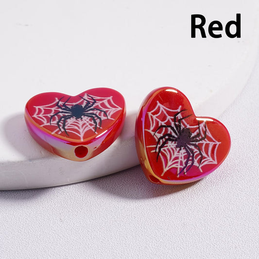 Heart-shaped red earrings with spider design on a white background

