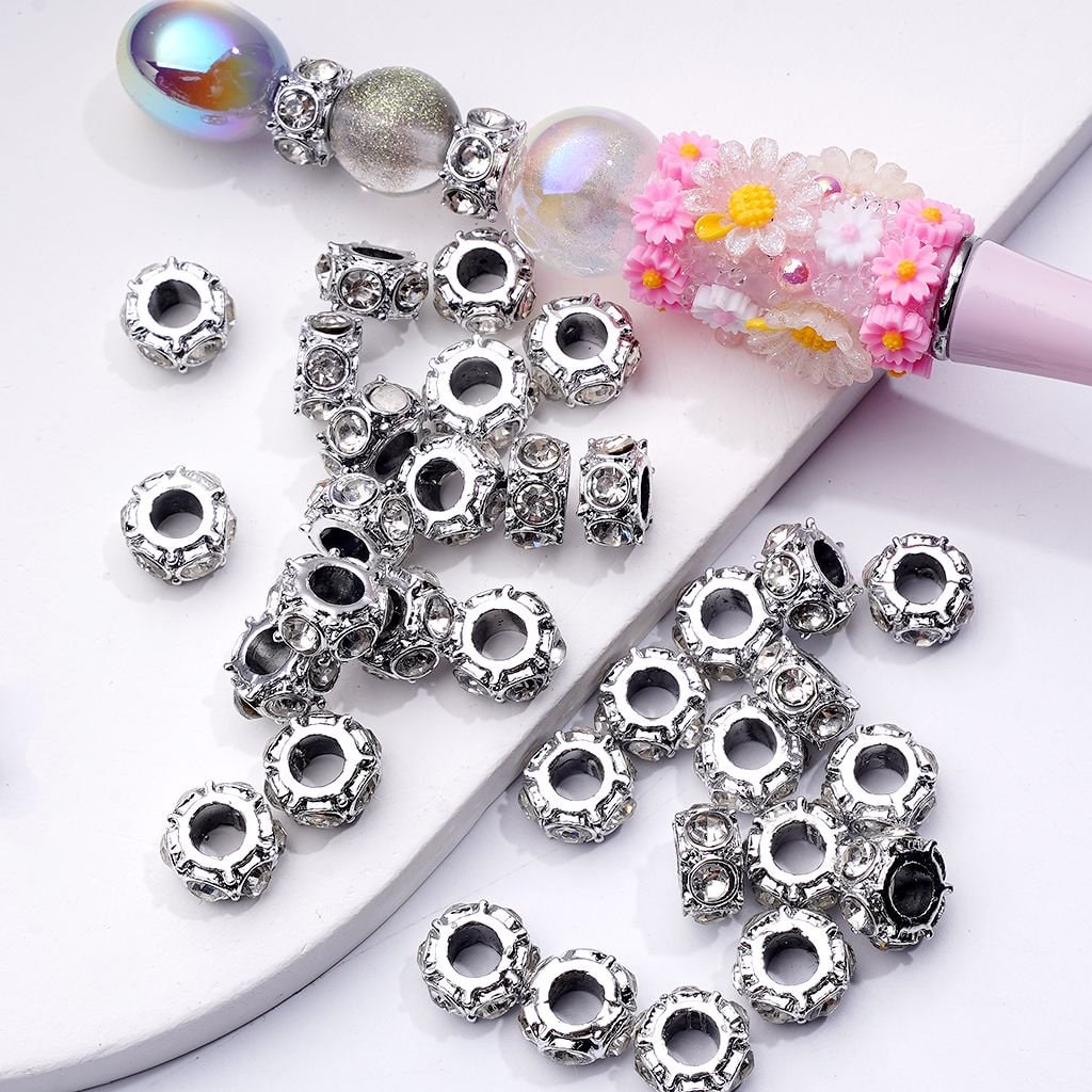 Silver beads with rhinestones on a white surface

