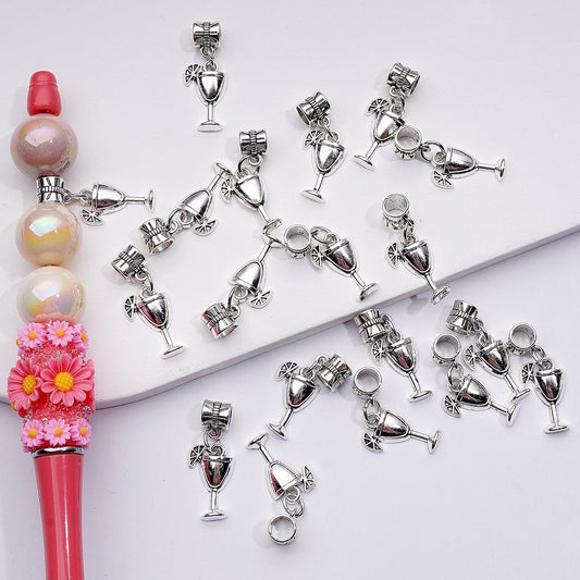 Silver wine glass charms on a white surface with a pink and pearl beaded item.

