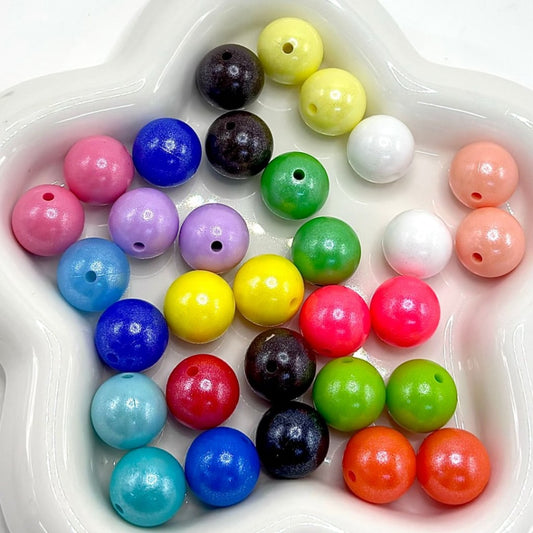 A collection of colorful pearl-style silicone beads with glittery finish, displayed in a random mix.

