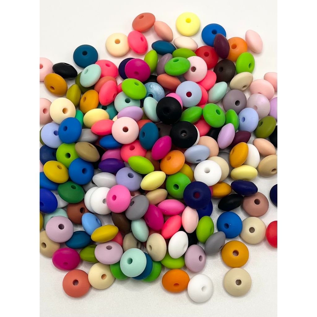 A collection of multicolored silicone beads spacers saucers, predominantly in round shape, with a hole in the center for stringing.


