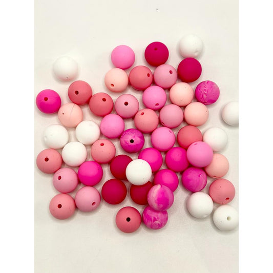 A collection of round silicone beads in various shades of pink, red, white, and purple with holes in the center for stringing.

