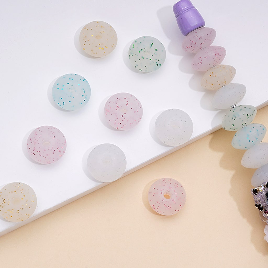 A collection of round silicone beads in various colors including white, pink, blue, and green, displayed on a flat surface.

